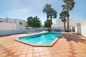 a swimming pool with chairs and palm trees at Ideal Villas Residence in Vila Nova De Cacela