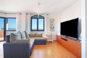 a living room with a couch and a flat screen tv at Vista de Lobos in Corralejo