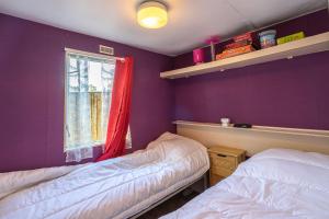 two beds in a room with purple walls and a window at Mh310 La Tremblade in La Tremblade