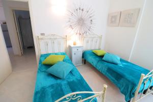 two beds in a white room with blue sheets at Casa Primus Torre Santo Stefano in Otranto