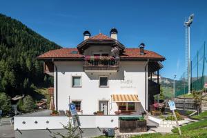 a white building with a balcony with flowers on it at Stoffel Apartments Martina in Selva