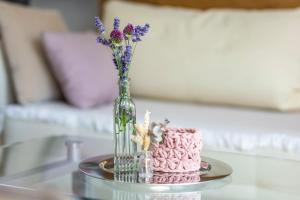 a glass vase with flowers and a pink cake on a table at Ferienwohnung Sonnenblick und Relax in Nieder-Röhre