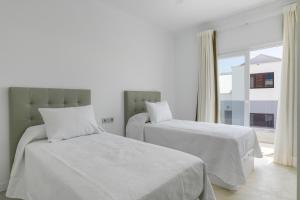 a bedroom with two beds with white sheets and a window at Dúplex El Equilibrio in Playa Honda
