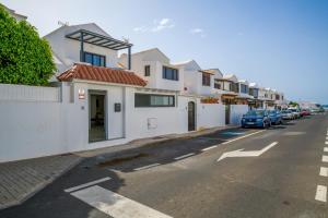 a street with white houses and cars parked on the street at Dúplex El Equilibrio in Playa Honda