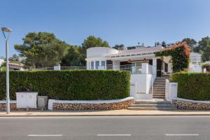 a white house with hedges in front of a street at V206 Villa Isabel in Son Bou