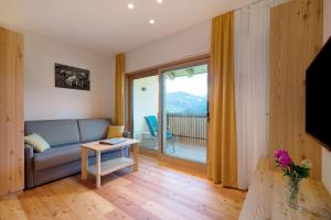 a living room with a couch and a large window at Teutenhofer Apfel in Feldthurns