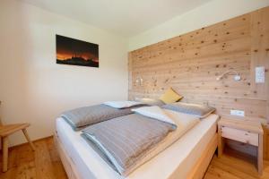 a bed in a room with a wooden wall at Teutenhofer Apfel in Feldthurns