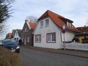 a white house with an orange roof on a street at An't Fischerspad in Wangerland