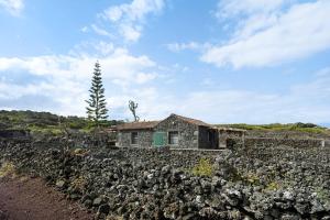 an old house in a field with a stone wall at Adega Maciel in Lajido