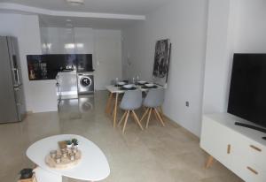 a living room with a table and a television at Great apartment with pool - jacuzi in Villacosta