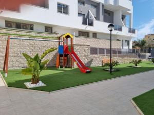 a playground in front of a building with a slide at Great apartment with pool - jacuzi in Villacosta