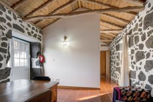 a living room with a stone wall and a table at Adega Maciel in Lajido