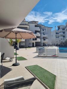 a patio with two umbrellas and a swimming pool at Great apartment with pool - jacuzi in Villacosta