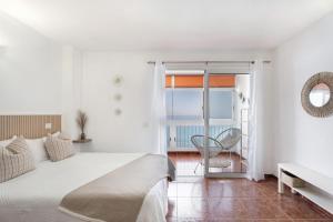 a white bedroom with a bed and a balcony at Apartamento Luna in Tacoronte