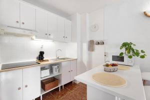 a kitchen with white cabinets and a table with a bowl of fruit at Apartamento Luna in Tacoronte