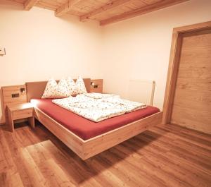 a bedroom with a bed in a room with wooden floors at Apartment Toni - Obermösslhof in Lana