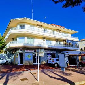 a large yellow building with cars parked in front of it at Apartamento Portosun Pez in Portocolom