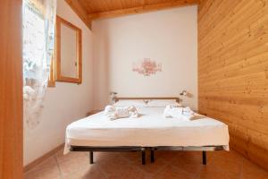 a bedroom with a bed with white sheets and wooden walls at Agriturismo Alimini a Otranto in Alimini