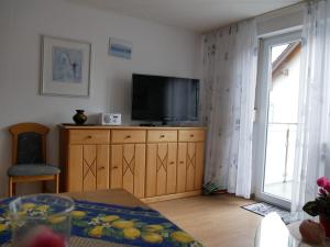 a living room with a television on a wooden dresser at Haus Alpenblick in Immenstaad am Bodensee