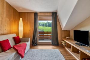 a living room with a couch and a television at Chalet Hubertus in Kastelruth