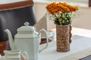 a table with a tea pot and a vase of flowers at Ferienwohnung Elim in Olsberg