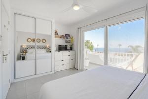 a white bedroom with a view of the ocean at La Perla in Callao Salvaje