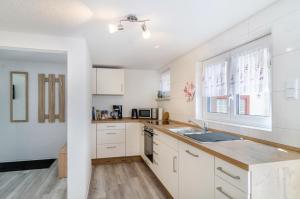a kitchen with white cabinets and a sink at Mina in Krauchenwies +20 photos