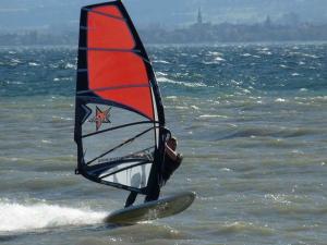 a person on a surfboard with a sail on the ocean at Haus Alpenblick in Immenstaad am Bodensee +27 photos