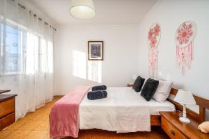 a bedroom with a bed with white walls and windows at Casa Quintião in Ferragudo