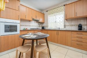 a kitchen with wooden cabinets and a table and chairs at Casa Quintião in Ferragudo