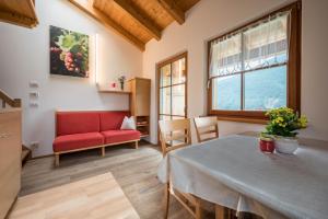 a living room with a table and a red chair at Kreuzhof rechts in Novacella