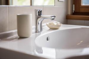 a bathroom sink with a faucet and a cup on it at Kreuzhof rechts in Novacella