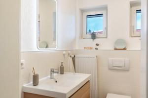 a white bathroom with a sink and two windows at Fewokuh in Wilhelmshaven +20 photos