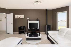 a living room with a white couch and a tv at Villa Lumière Ychoux in Ychoux