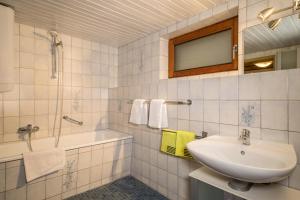 a bathroom with a sink and a tub and a mirror at Ferienwohnung im alten Forsthaus in Bermatingen +18 photos