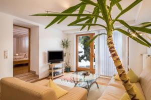 a living room with a couch and a palm tree at Ferienwohnung im alten Forsthaus in Bermatingen