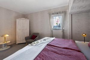 a bedroom with a bed and a chair and a window at Ferienhaus Harmonie in Südbrookmerland