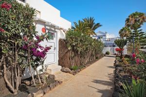a walkway in front of a white house with flowers at Isla Lobos in Playa Blanca