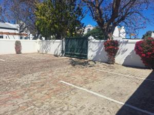 a parking lot with flowers in front of a white fence at De Kothuize 16 in Graaff-Reinet