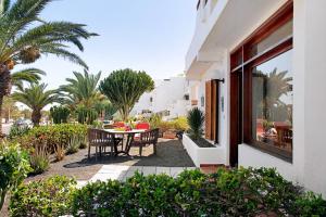 a patio with a table and chairs and palm trees at Isla and Ocean with pool and wifi in Costa Teguise