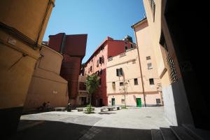 an alley with buildings and a tree in the middle at Abbey Hostel in Genoa