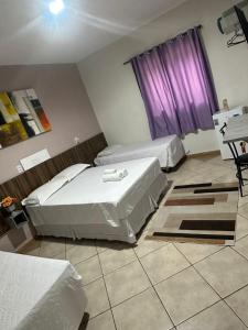 a bedroom with two beds and a purple window at Itaipu Hotel in Foz do Iguaçu +24 photos
