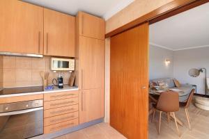 a kitchen with wooden cabinets and a table in a room at Sunrise Salgados Village in Galé