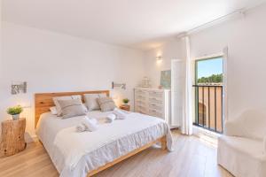 a white bedroom with a large bed and a window at Es Clos in El Port de la Selva