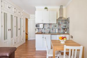 a kitchen with a wooden table and white cabinets at House Sun Beach 2 in Vejer de la Frontera