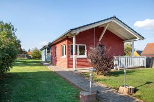 a red house in a yard with a yard at Ferienhäuser Hainichhöhe in Hörselberg-Hainich