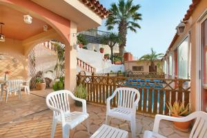 a patio with white chairs and a fence and palm trees at Villa Petite Paradise in Las Lagunas