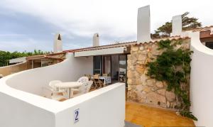 a white house with a stone wall and a patio at Villa Estrellas 2 in Cala en Bosc