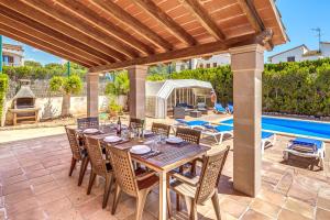 a wooden table and chairs on a patio with a pool at Villa Isabel in Campos