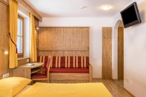 a bedroom with a bed and a desk and a television at Wollbach - Gruberhof in San Giacomo